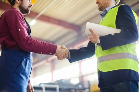 Engineer and foreman shake hands after successfully discussing a new project. Stock Photos