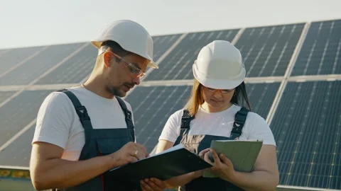 An engineer and a technician are discussing the result of a solar power plant Stock Footage 256108513