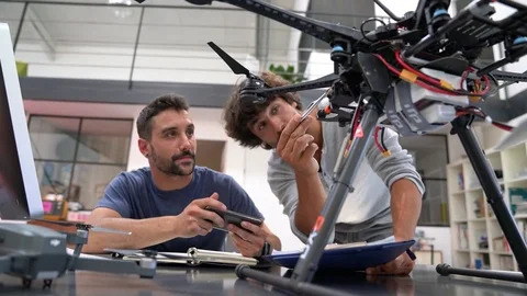 Engineer and technician working together on drone in office Stock Footage