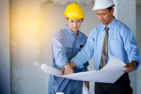 Engineer and worker checking plan on construction site Stock Photos