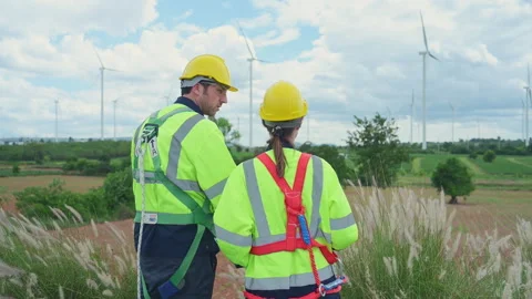Engineer and worker discussing the project on the background of wind turbines Stock Footage 254004213