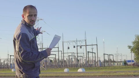 Engineer and Worker at Electrical Substation. Worker with blueprints and Stock Footage 90467919