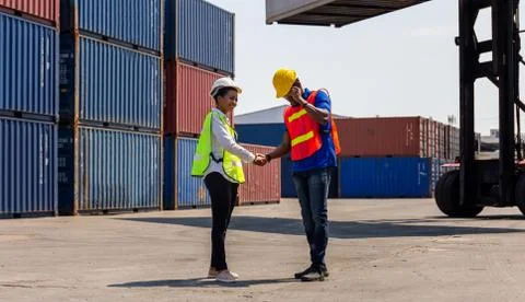 Engineer and worker handshake with blurred containers cargo background, Succe 스톡 사진