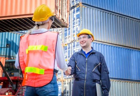 Engineer and worker handshake with blurred containers cargo background Фото