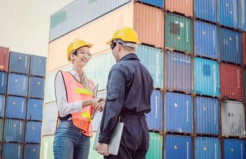 Engineer and worker handshake with blurred containers cargo background 写真素材