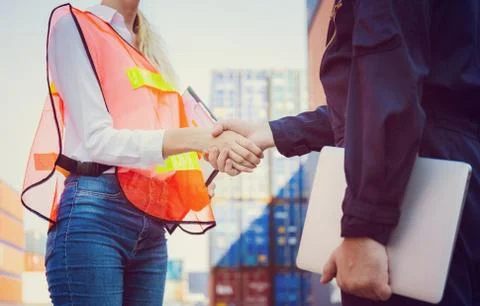 Engineer and worker handshake with blurred containers cargo background Stockfoto's