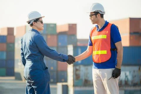 Engineer and worker handshake with blurred containers cargo background Photos