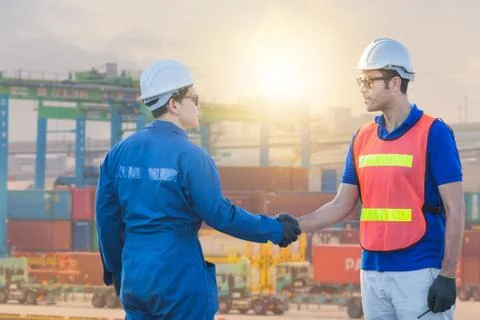 Engineer and worker handshake with blurred containers cargo background Фото