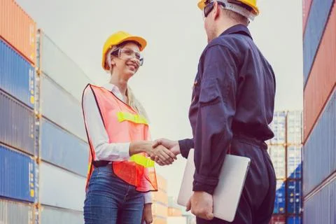 Engineer and worker handshake with blurred containers cargo background Stockfoto's
