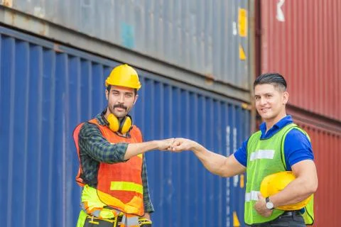 Engineer and worker making a fist bump with blurred containers cargo background Fotos de archivo
