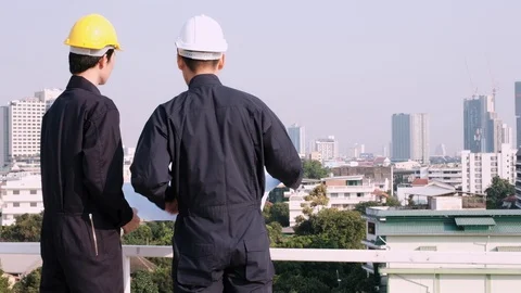 Engineer and worker standing on construction site and look at blueprint Stock Footage 129584897