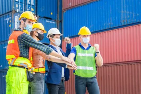 Engineer and worker team joining hands and celebration with blurred cargo Фото