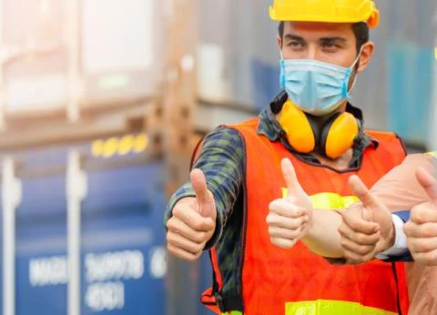 Engineer and worker team wearing protection face mask with giving thumbs up Stock Photos