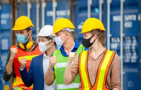 Engineer and worker team wearing protection face mask with celebration at cargo Фото