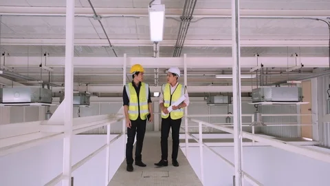 Engineer and worker walking on skywalk in building and watch blueprint. Stock Footage 129584626