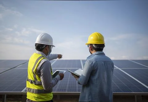 Engineer and worker working together in the solar panel power station renewab Stock Photos