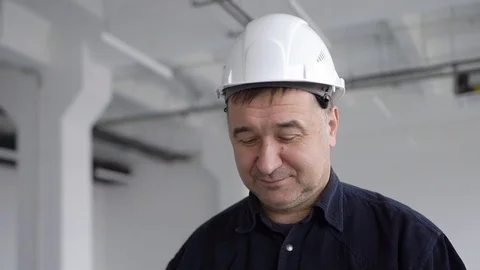 Engineer, architect in a blue shirt, puts on glasses and smiles Stock Footage 126242758