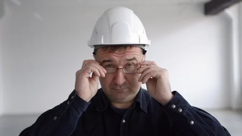 Engineer, architect in a blue shirt, puts on glasses and smiles Stock Footage 126242788