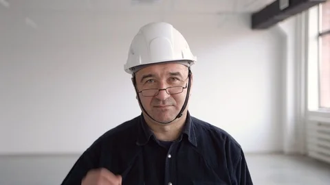Engineer, architect in a blue shirt, puts on glasses and smiles Stock Footage 126242892
