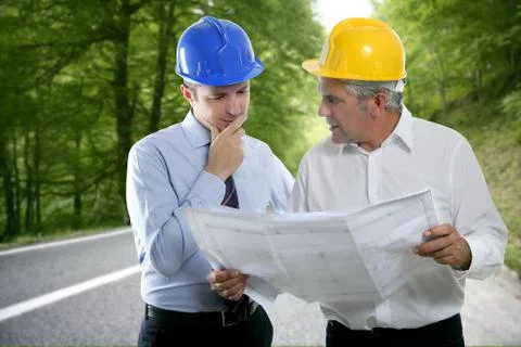Engineer architect two expertise plan hardhat forest road Stock Photos