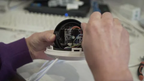 An engineer assembles and repairs a CCTV camera in a workshop. Hands of a man Stock Footage 142725761