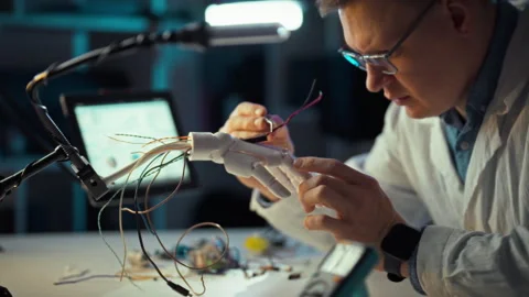 Engineer assembles robotic hand in workshop focusing on advanced technology Stock Footage 331298011