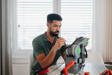 Engineer assembling and coding a robotic arm at home as part of a robotics Foto stock