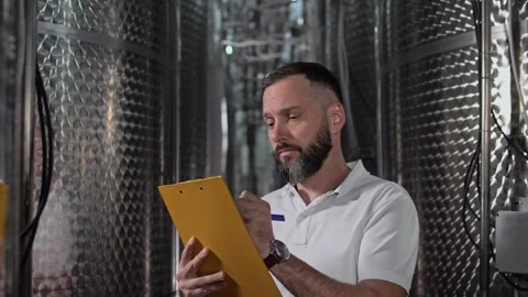 Engineer with beard making a tour and inspection of winemaking equipment. Stock Footage 270058296