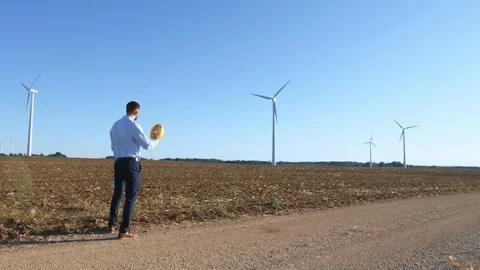 The engineer begins work on the drawings against the background of windmills Stock-Footage 76572695