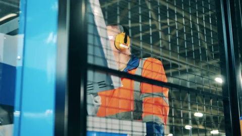 Engineer is being shot through a grid while operating a factory machine Stock-Footage 147644224
