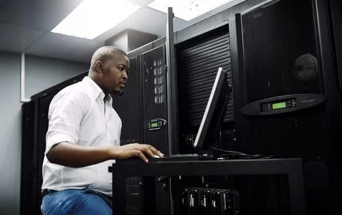Engineer, black man or coding on laptop in server room for big data, network Stock Photos