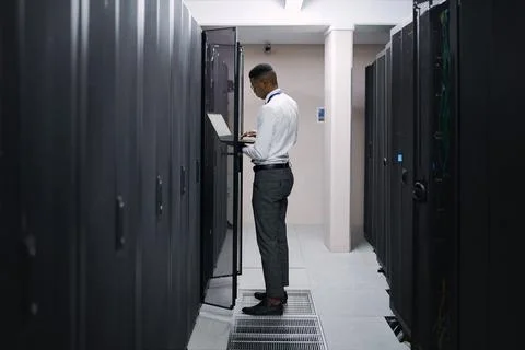 Engineer, black man or typing on laptop in server room for console access, .. Stock Photos
