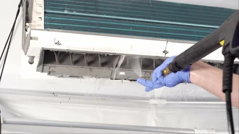 Engineer in blue gloves and mask cleaning dirty air conditioner from dust and Video stock 131904311