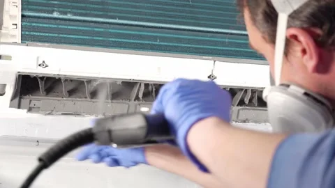 Engineer in blue gloves and mask cleaning dirty air conditioner from dust and Video stock 131904710