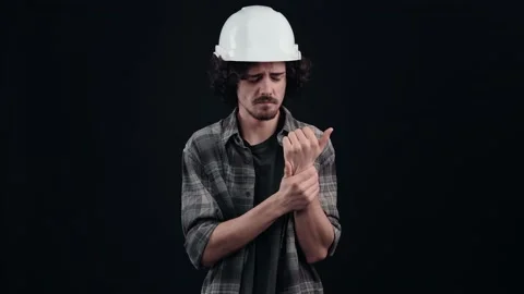 The engineer boy with the white helmet, sadly clings to his wrist, suffers from Stock Footage 156277531