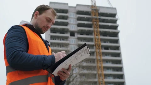Engineer builder on the construction site takes notes on the drawings Stock Footage 88525457