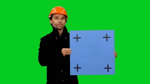 Engineer builder in hard hat holding blue blank board on green screen Stock Footage 130836296