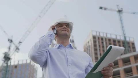 Engineer builder using tablet and walkie talkie, giving instructions at a Stock Footage 111763157
