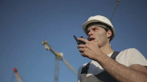 Engineer builder using a walkie talkie giving instructions at construction site Stock Footage 53605400
