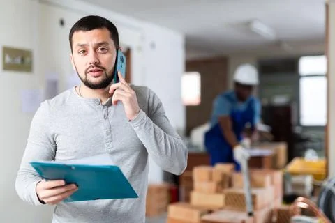 Engineer of building under construction discussing repair plan on mobile phone Stock Photos