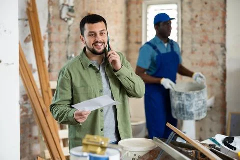 Engineer of building under construction discussing repair plan on mobile phone Stock Photos