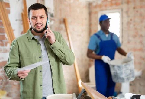 Engineer of building under construction discussing repair plan on mobile phone Stock Photos