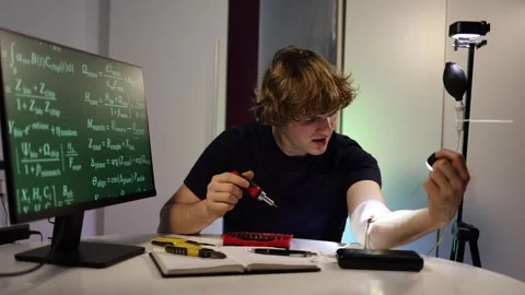Engineer calibrates glowing arm implant while coding neural systems in home lab Stock Footage 324442928