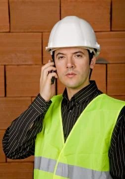Engineer calling with white hat with a brick wall as background Stock Photos