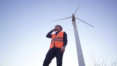 Engineer of the Caucasian appearance stands confidently near the windmill and Stock Footage 124483501
