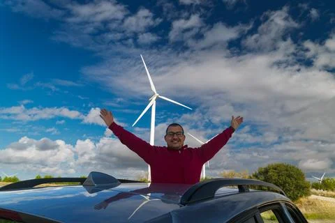Engineer celebrating renewable energy at wind turbine farm with open arms Stock Photos