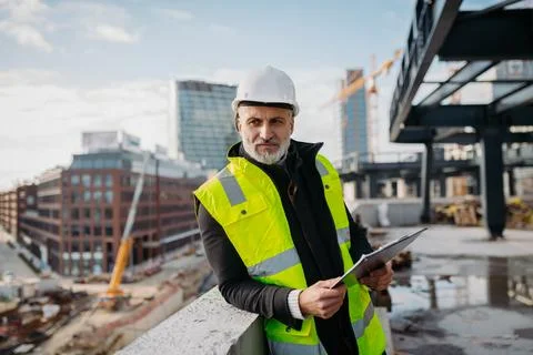 Engineer checking building documentation on clipboard at construction site. Fotos de archivo