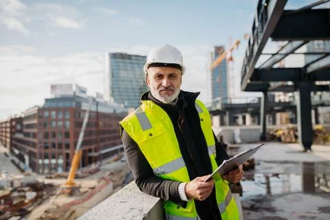 Engineer checking building documentation on clipboard at construction site. Fotos de archivo