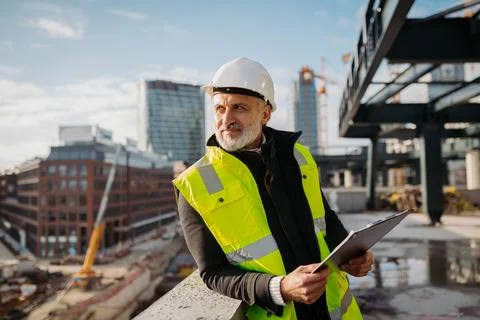 Engineer checking building documentation on clipboard at construction site. Fotos de archivo