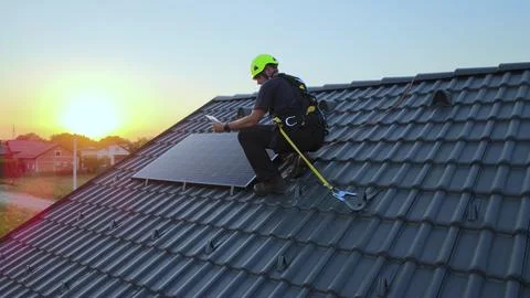 Engineer checking data on tablet, while installing solar panels on a house 写真素材